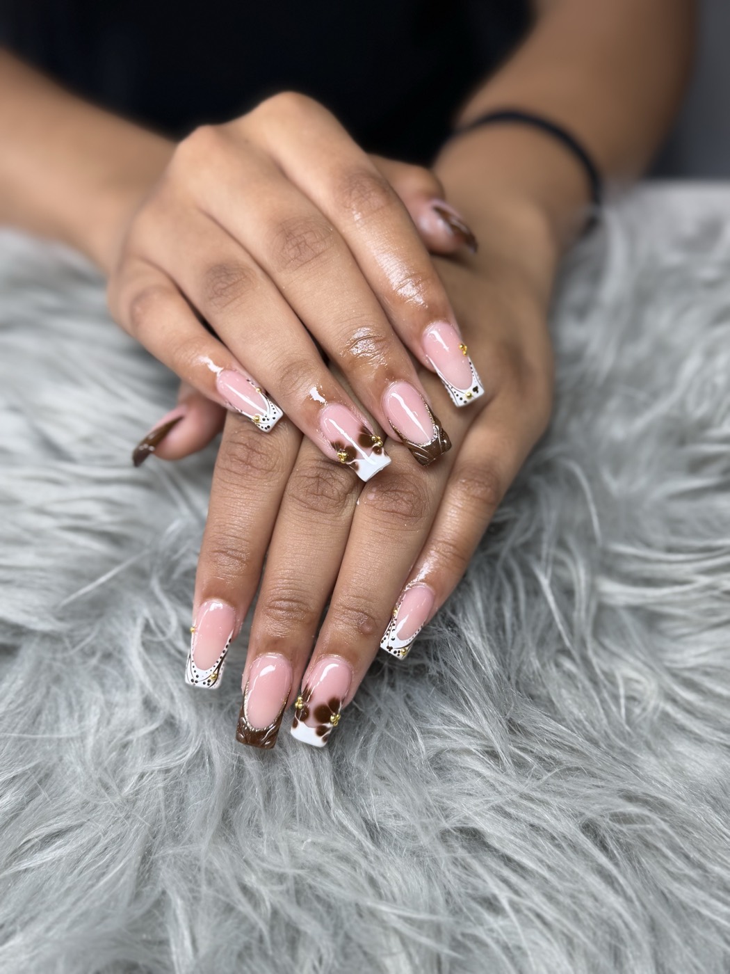 Square French tips in brown and white with hand-painted cow print and gold beads